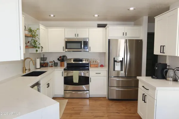 a kitchen with a refrigerator a stove top oven a sink and cabinets