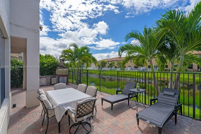 a patio with table and chairs potted plants and a palm tree