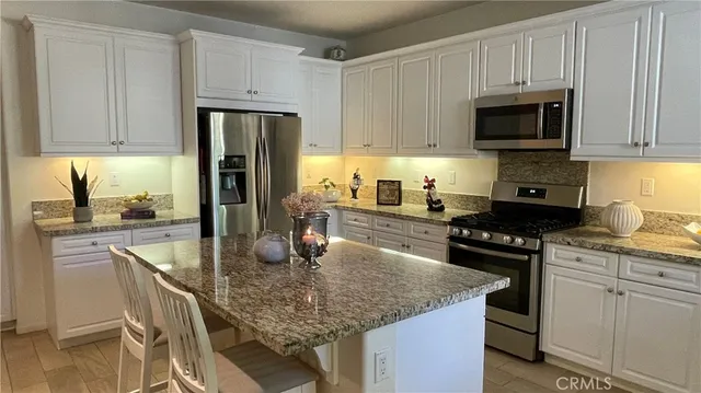 a kitchen with kitchen island granite countertop a sink a stove and refrigerator