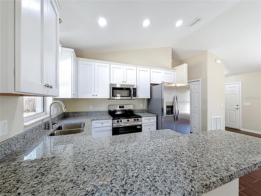 1314 Southwest 68th Avenue Bushnell, FL 33513 - Photo 21 of 33 a kitchen with granite countertop a refrigerator sink and cabinets