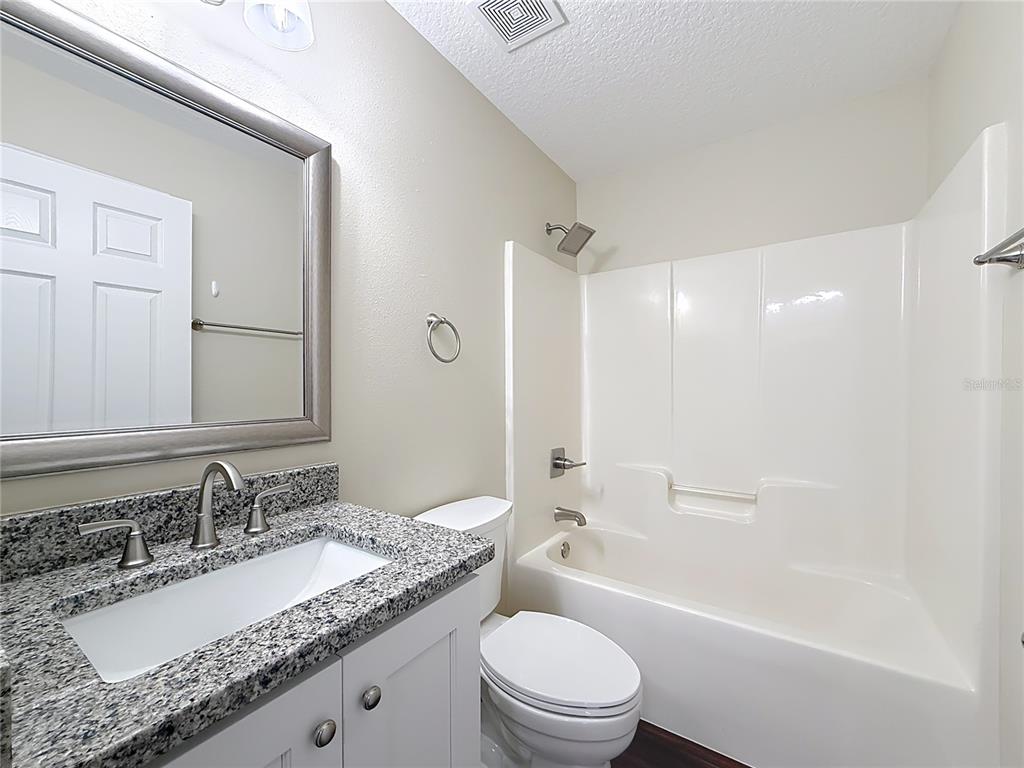 1314 Southwest 68th Avenue Bushnell, FL 33513 - Photo 30 of 33 a bathroom with a granite countertop sink mirror toilet and bathtub