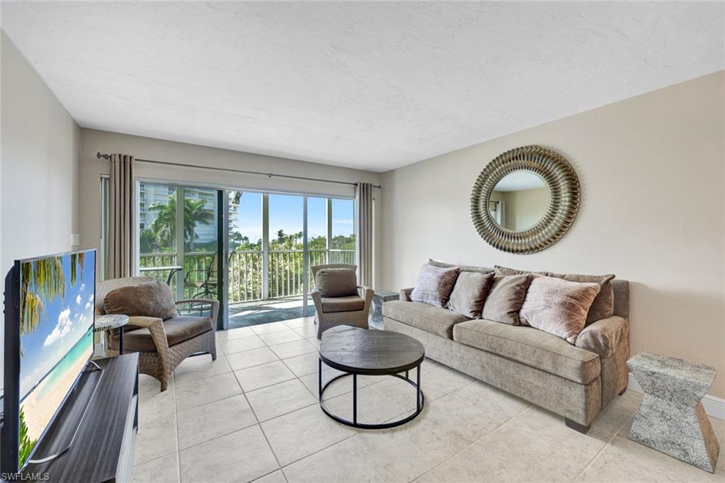 1 Bluebill Avenue, Unit 409 Naples, FL 34108 - Photo 1 of 25 a living room with furniture a floor to ceiling window and a large window