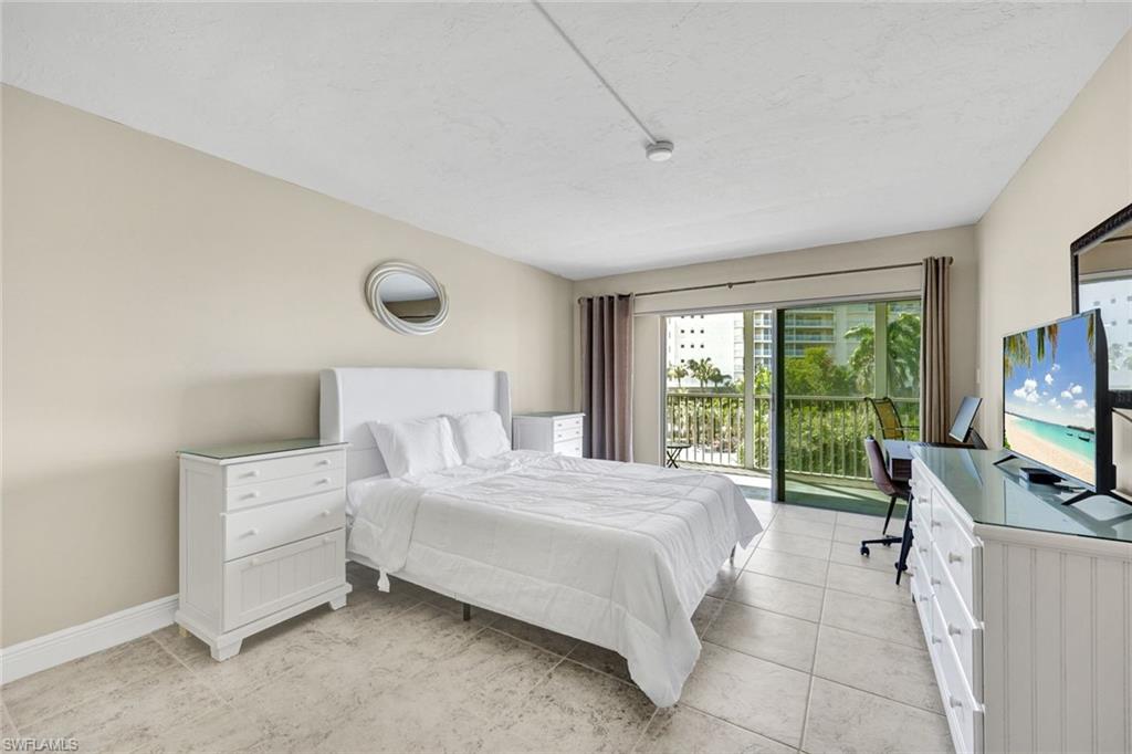 1 Bluebill Avenue, Unit 409 Naples, FL 34108 - Photo 12 of 25 a bedroom with a bed and tv