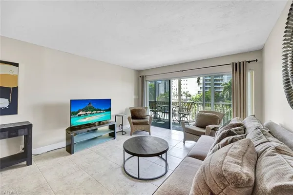a living room with furniture a floor to ceiling window and a flat screen tv