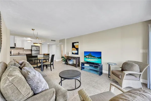 a living room with furniture and a flat screen tv with kitchen view