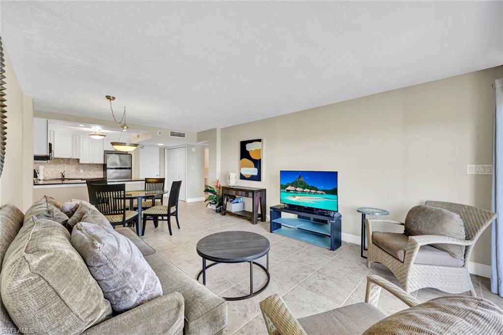 1 Bluebill Avenue, Unit 409 Naples, FL 34108 - Photo 3 of 25 a living room with furniture and a flat screen tv with kitchen view