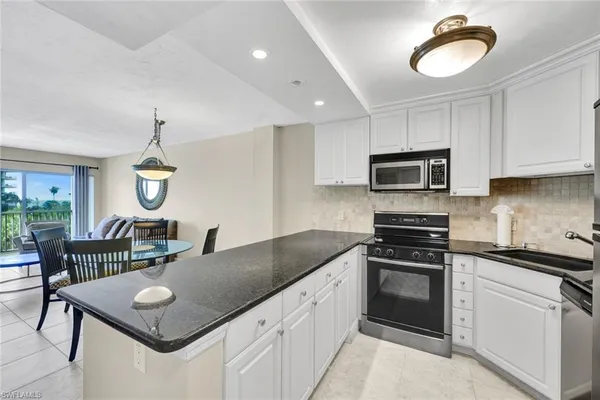 a kitchen with granite countertop stainless steel appliances a stove sink microwave and cabinets