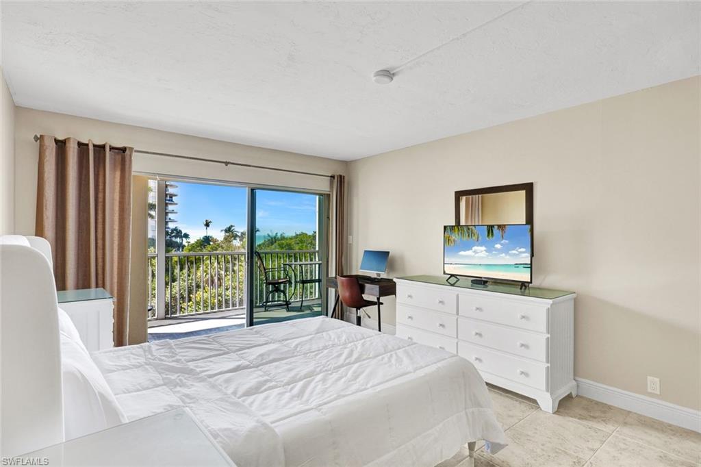 1 Bluebill Avenue, Unit 409 Naples, FL 34108 - Photo 9 of 25 a bedroom with furniture and a flat screen tv