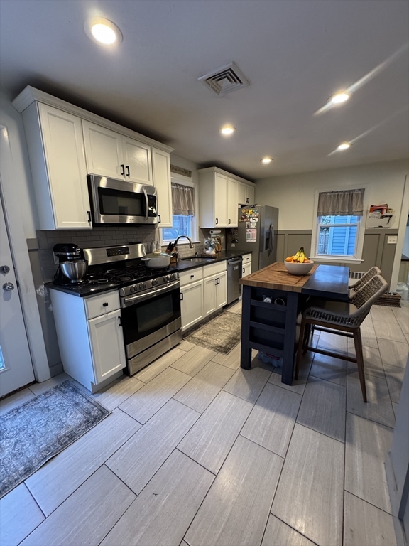9 Rochambeau Street Fairhaven, MA 02719 - Photo 7 of 18 a kitchen with stainless steel appliances granite countertop a stove top oven a sink dishwasher a dining table and chairs with wooden floor