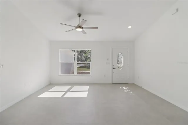 an empty room with windows and fan