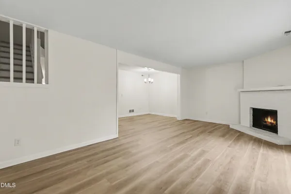 a view of an empty room with wooden floor fireplace and a window