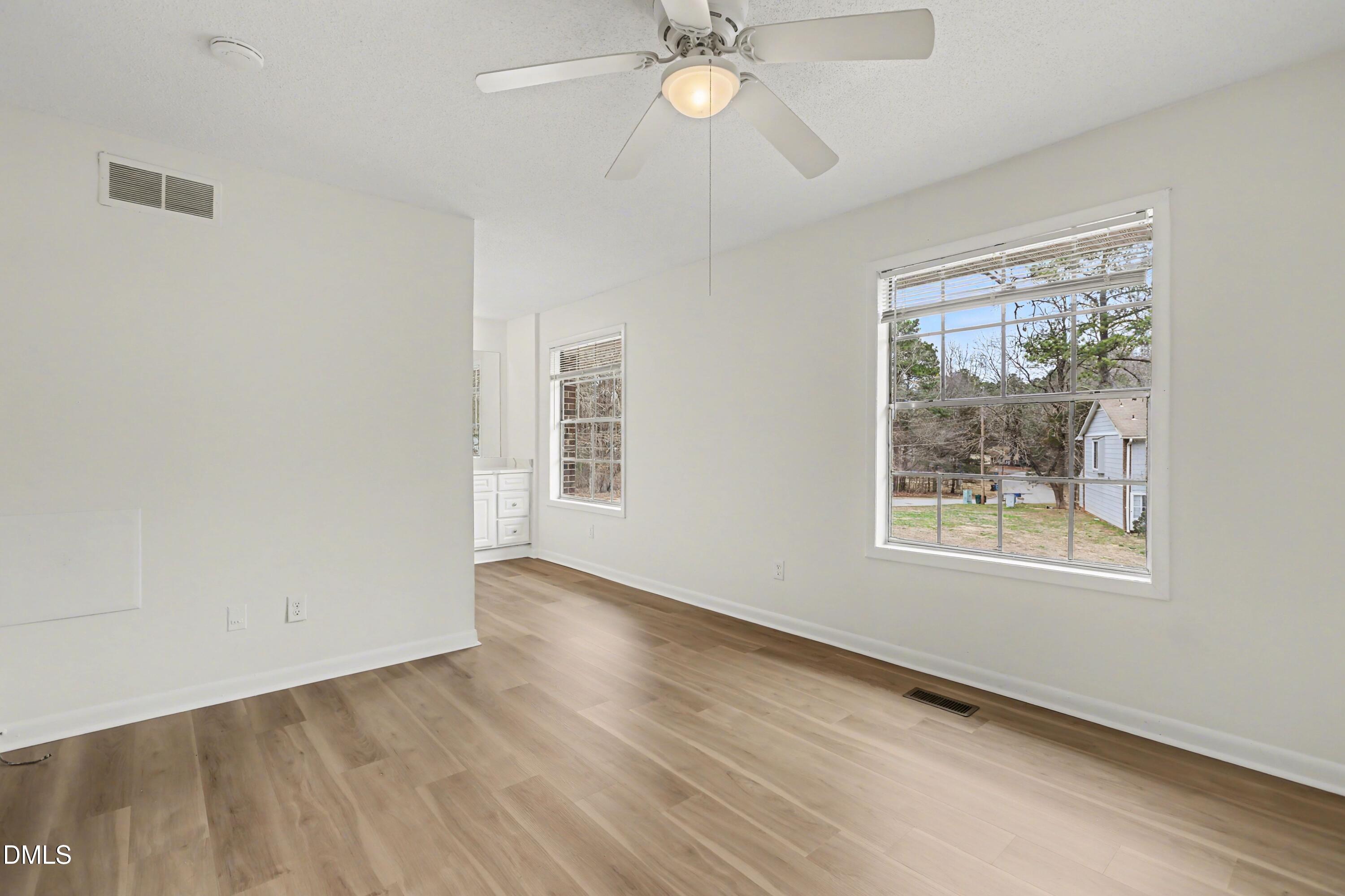 1304 Seaton Road, Unit 30 Durham, NC 27713 - Photo 19 of 25 an empty room with wooden floor chandelier fan and windows