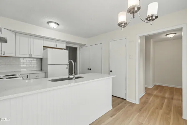 a kitchen with a refrigerator a stove cabinets and wooden floor