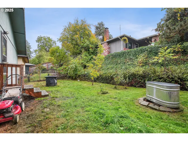 a view of a backyard with plants and wooden fence