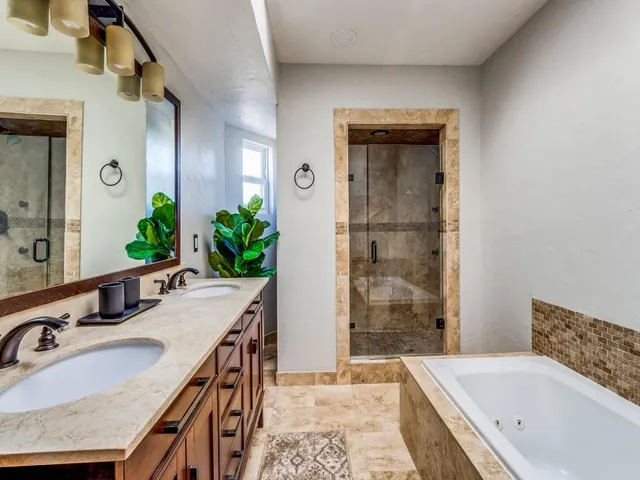 a bathroom with a granite countertop tub sink and mirror
