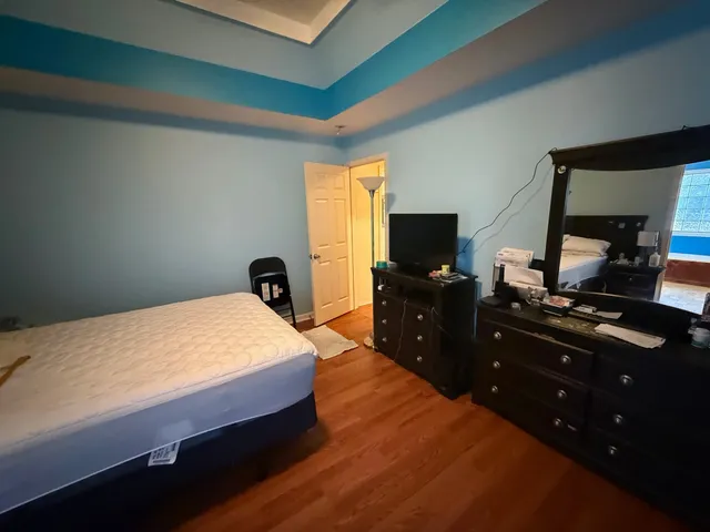 a bedroom with a bed and a flat tv screen on a dresser