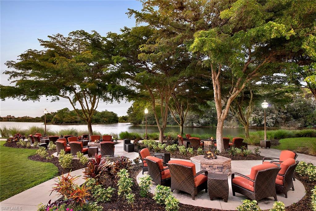 10911 Oak Island Road, Unit 201 Estero, FL 34135 - Photo 23 of 24 a view of a patio with couches table and chairs under an umbrella with a big yard