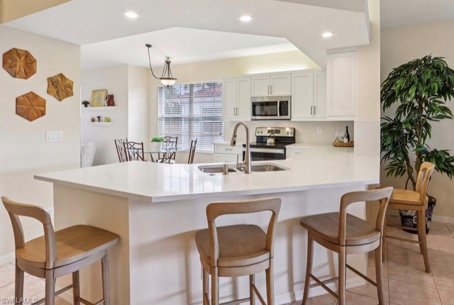 10911 Oak Island Road, Unit 201 Estero, FL 34135 - Photo 3 of 24 a kitchen with stainless steel appliances kitchen island granite countertop a dining table chairs and a refrigerator