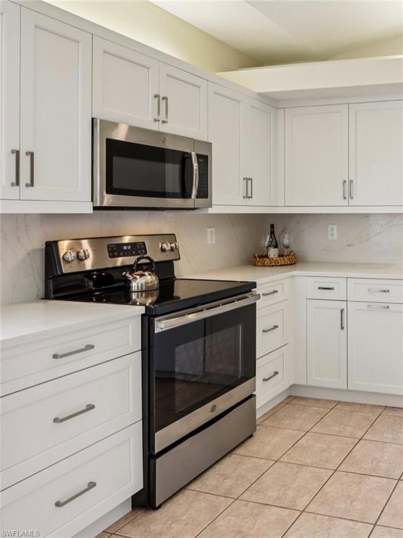 10911 Oak Island Road, Unit 201 Estero, FL 34135 - Photo 6 of 24 a kitchen with white cabinets and stainless steel appliances