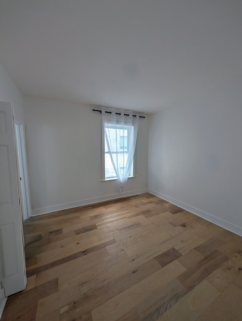 616 West Patterson Avenue, Unit 2E Chicago, IL 60613 - Photo 6 of 18 an empty room with wooden floor and windows