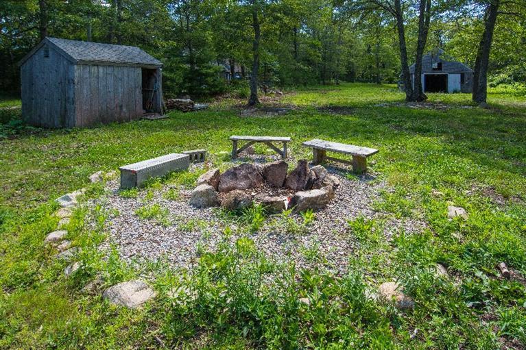 105 Cammett Road Marstons Mills, MA 02648 - Photo 18 of 21 a view of a backyard with table and chairs and wooden fence