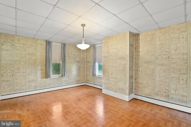 an empty room with chandelier fan and windows