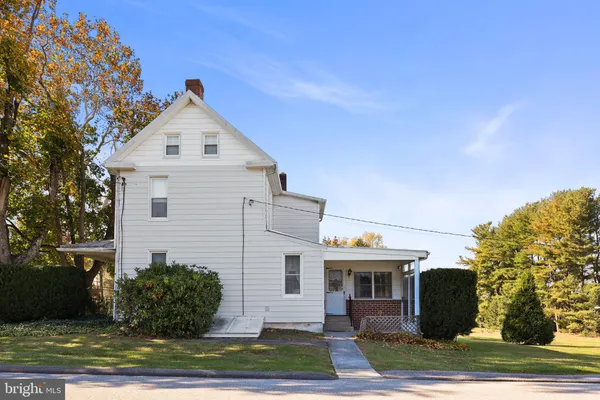 a view of a white house next to a yard