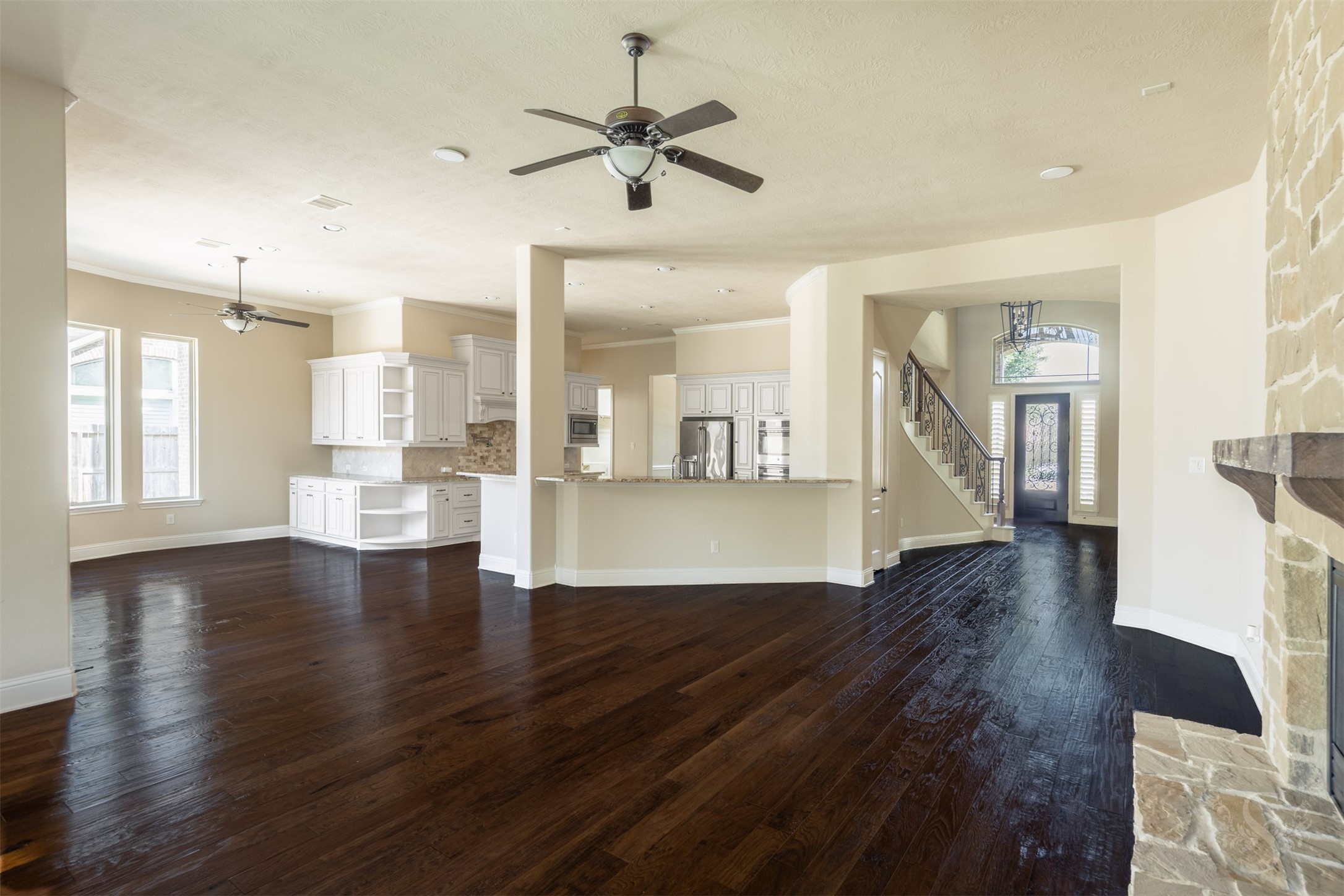 5803 Mustang Ridge Lane Fulshear, TX 77441 - Photo 10 of 48 Open-concept living spaces blend the family room, kitchen and breakfast area into one expansive gathering space. Rich wood flooring and a wall of windows create a warm, inviting atmosphere throughout the main living areas.