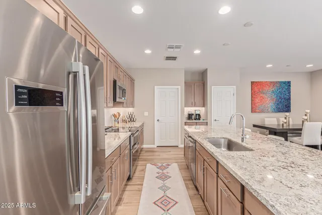 a kitchen with stainless steel appliances granite countertop a refrigerator a stove and a sink with wooden floor