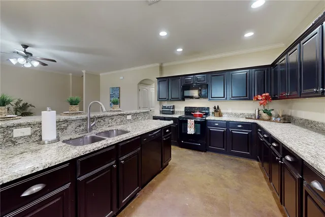 a kitchen with granite countertop a sink stainless steel appliances and window