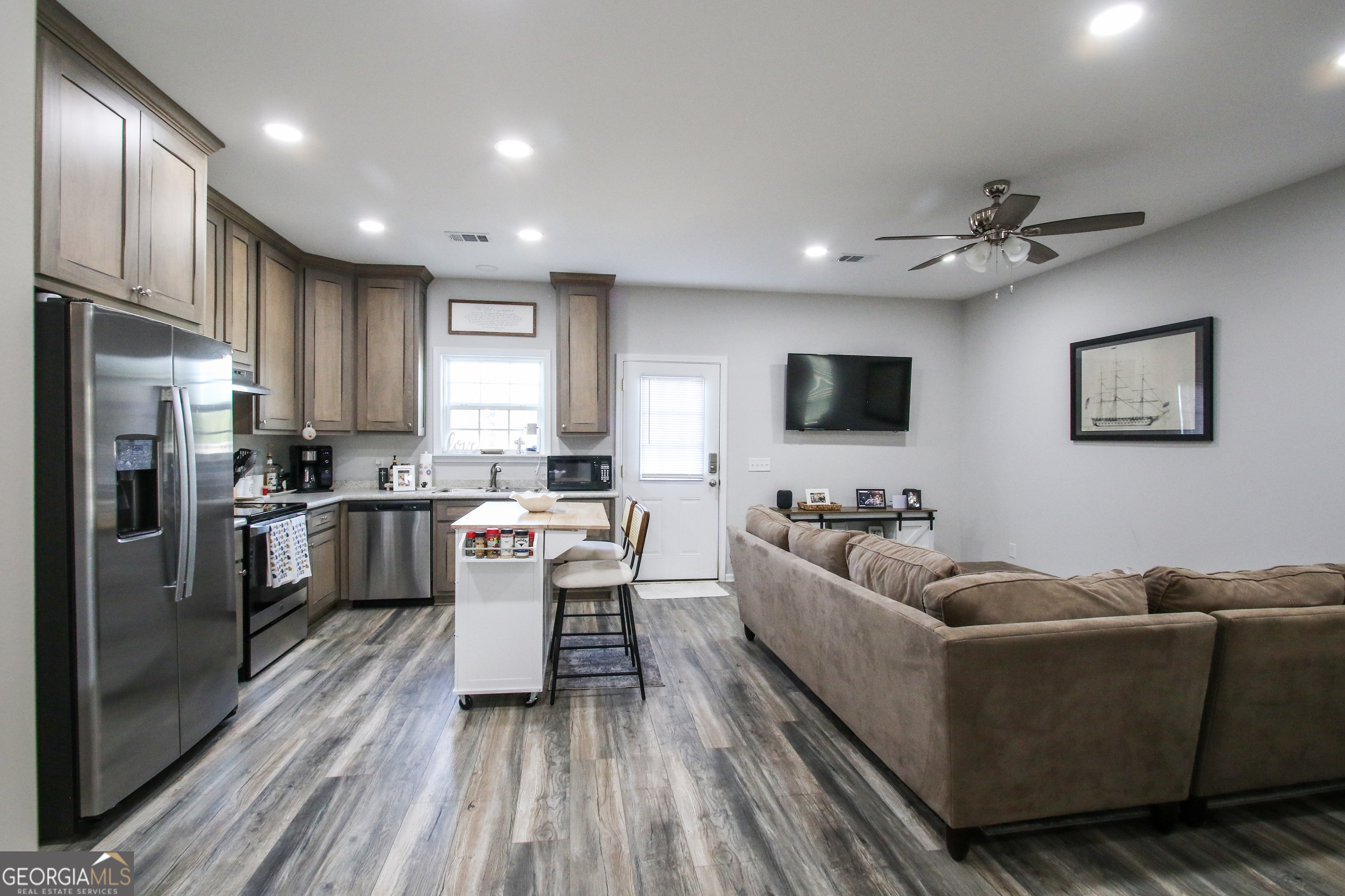 11769 Henry Street Collins, GA 30421 - Photo 14 of 51 a living room with stainless steel appliances furniture a flat screen tv and a kitchen view
