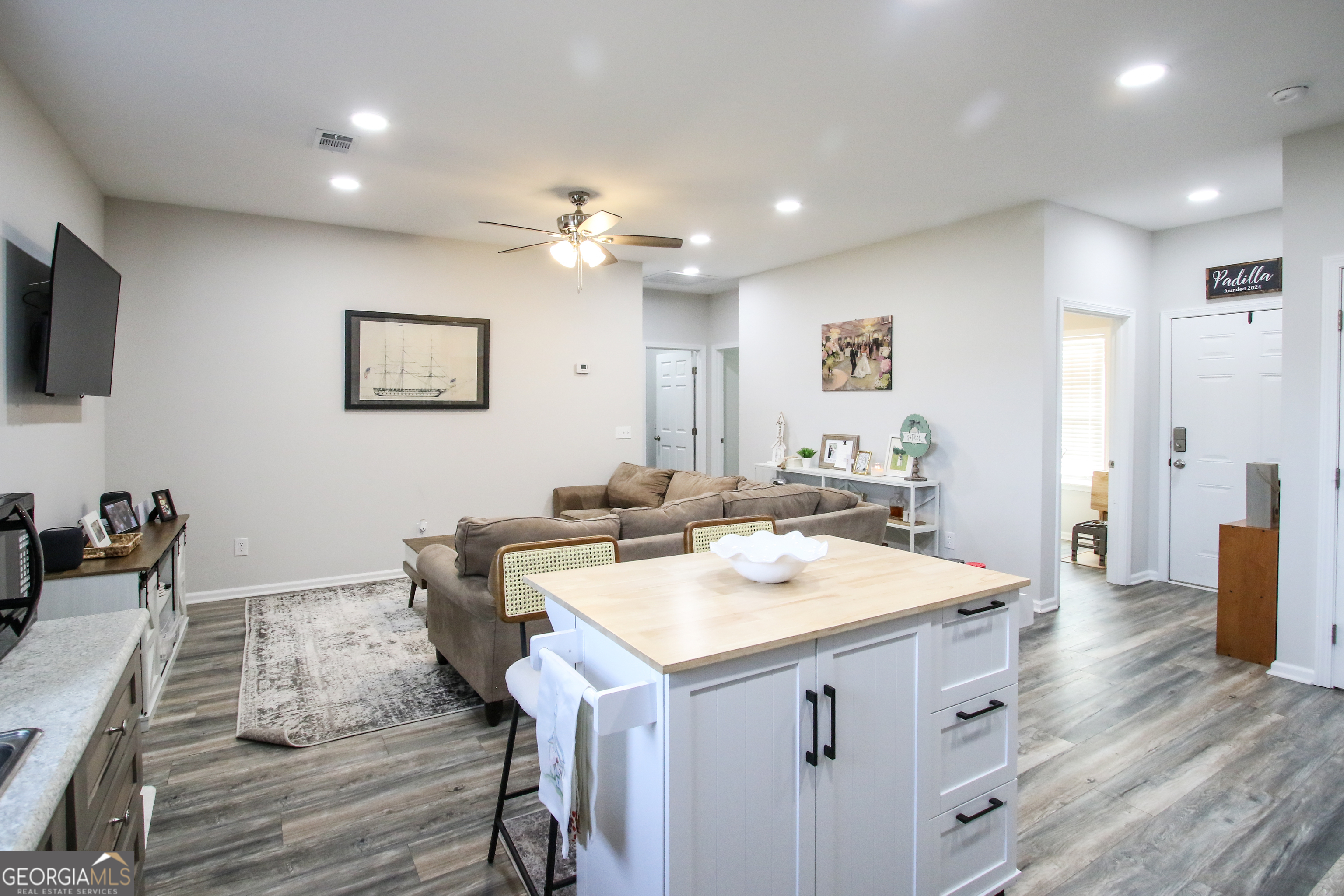 11769 Henry Street Collins, GA 30421 - Photo 19 of 51 a view of kitchen island a sink wooden floor and a living room