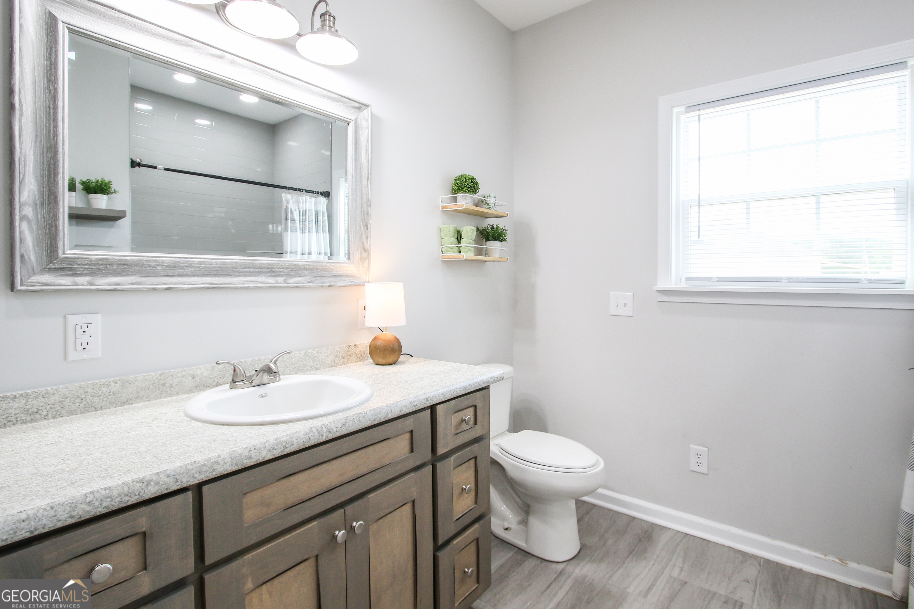 11769 Henry Street Collins, GA 30421 - Photo 51 of 51 a bathroom with a granite countertop sink a toilet and a mirror