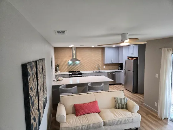 a living room with stainless steel appliances furniture and a refrigerator