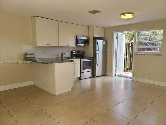 a kitchen with granite countertop a stove a sink and a refrigerator