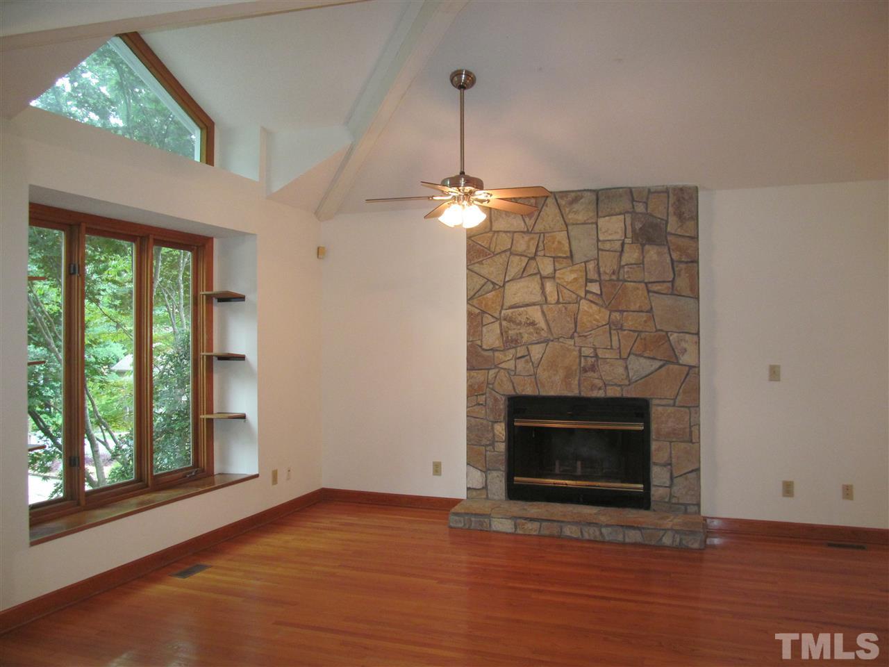 8321 Stryker Court Raleigh, NC 27615 - Photo 2 of 13 an empty room with windows fireplace and wooden floor