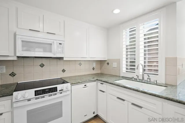 a kitchen with granite countertop white cabinets and white appliances