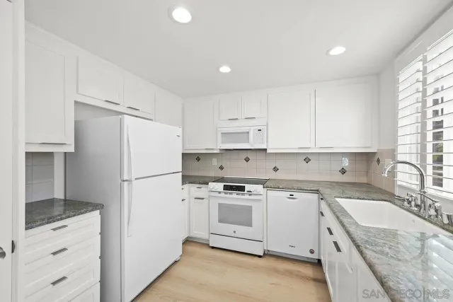 a kitchen with granite countertop white cabinets and white appliances