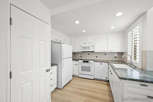 a kitchen with white cabinets and white appliances