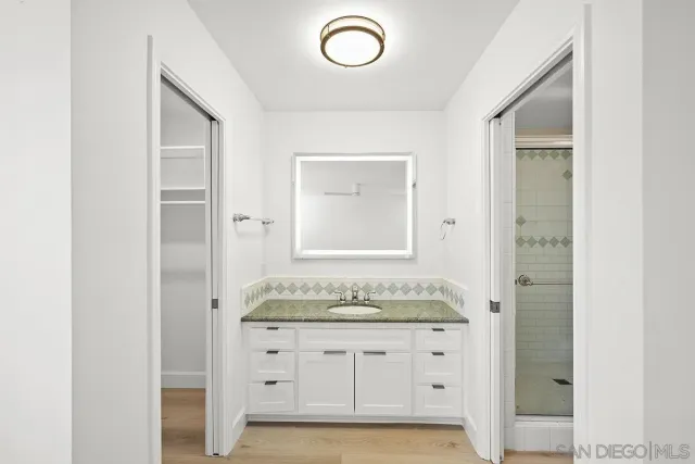 a bathroom with a granite countertop sink and a mirror
