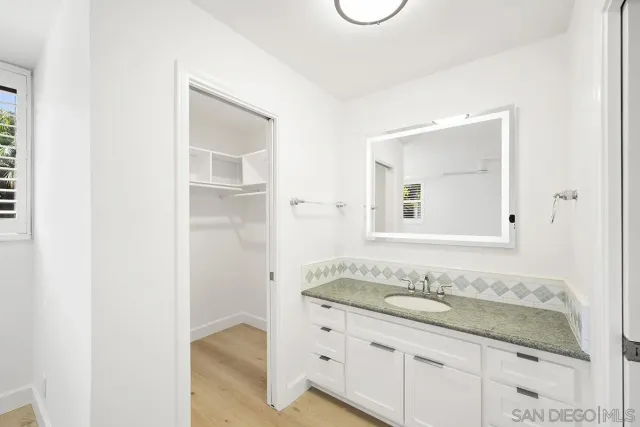 a bathroom with a granite countertop sink and a mirror