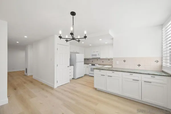 a kitchen with white cabinets and sink