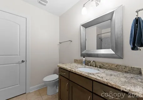 a bathroom with a granite countertop toilet sink and mirror