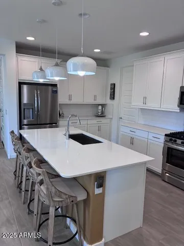 a kitchen with kitchen island granite countertop a sink a counter space appliances and cabinets