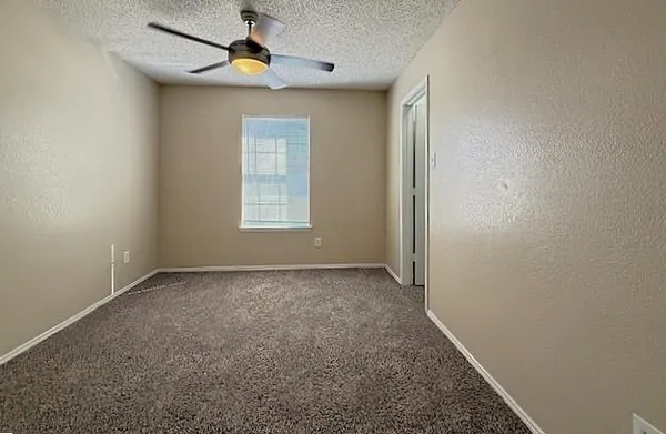 an empty room with a window and a fan