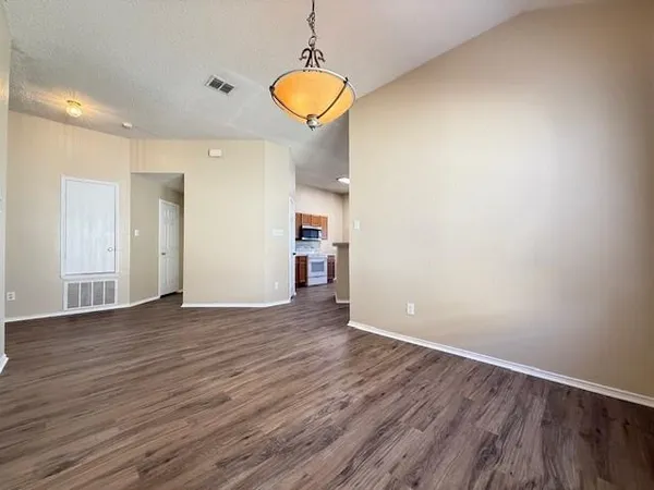 a view of empty room with wooden floor and window