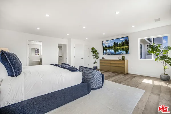 a spacious bedroom with a bed and a flat screen television