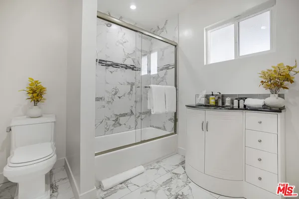 a bathroom with a granite countertop sink a toilet and shower