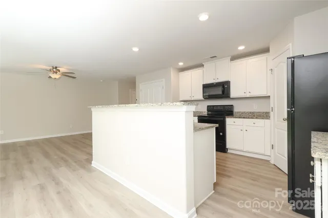 a kitchen with granite countertop white cabinets and black appliances