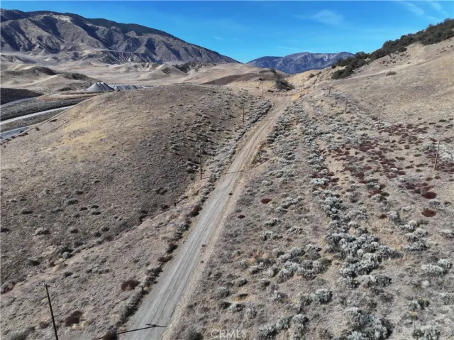 a view of a dry field with mountains in the background